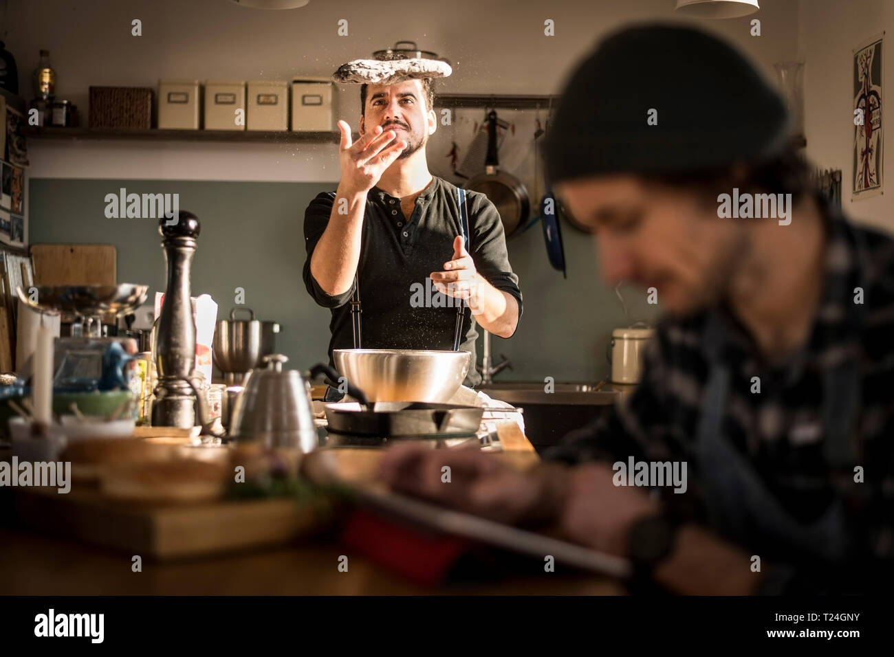 Un homme la préparation de pâte à pain tandis que l'autre est à l'aide de sa tablette numérique Banque D'Images