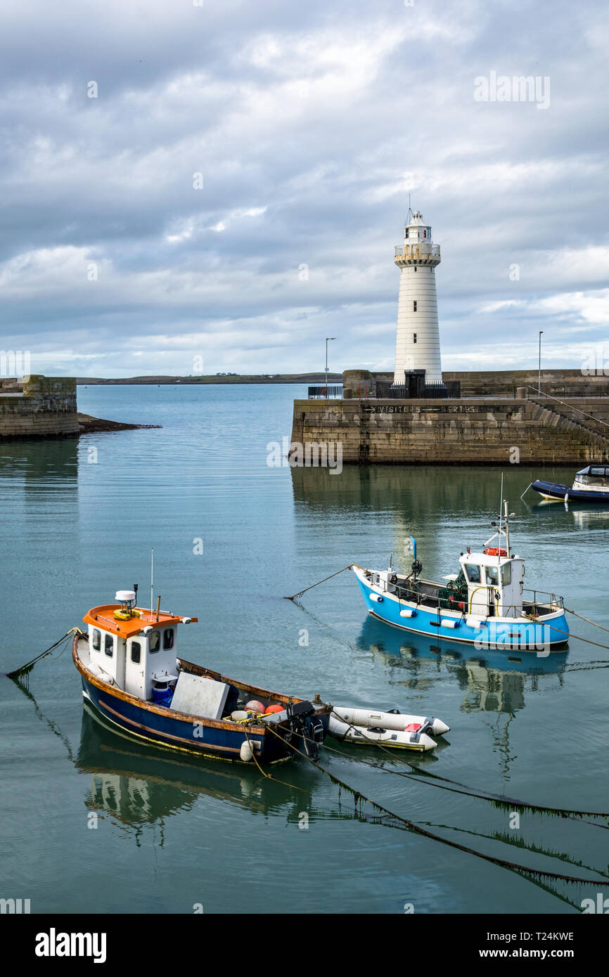 Il s'agit de Donaghadee Port et le phare sur la côte est de l'Irlande du Nord. Les bateaux de pêche sont ancrés dans l'eau calme Banque D'Images