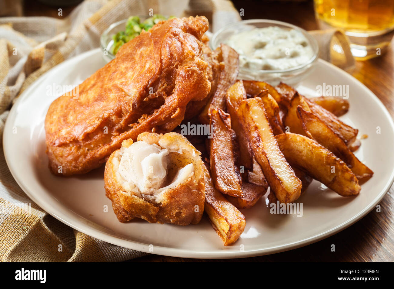 Le poisson dans la pâte traditionnelle de la bière et des frites avec de petits pois et sauce tartare Banque D'Images