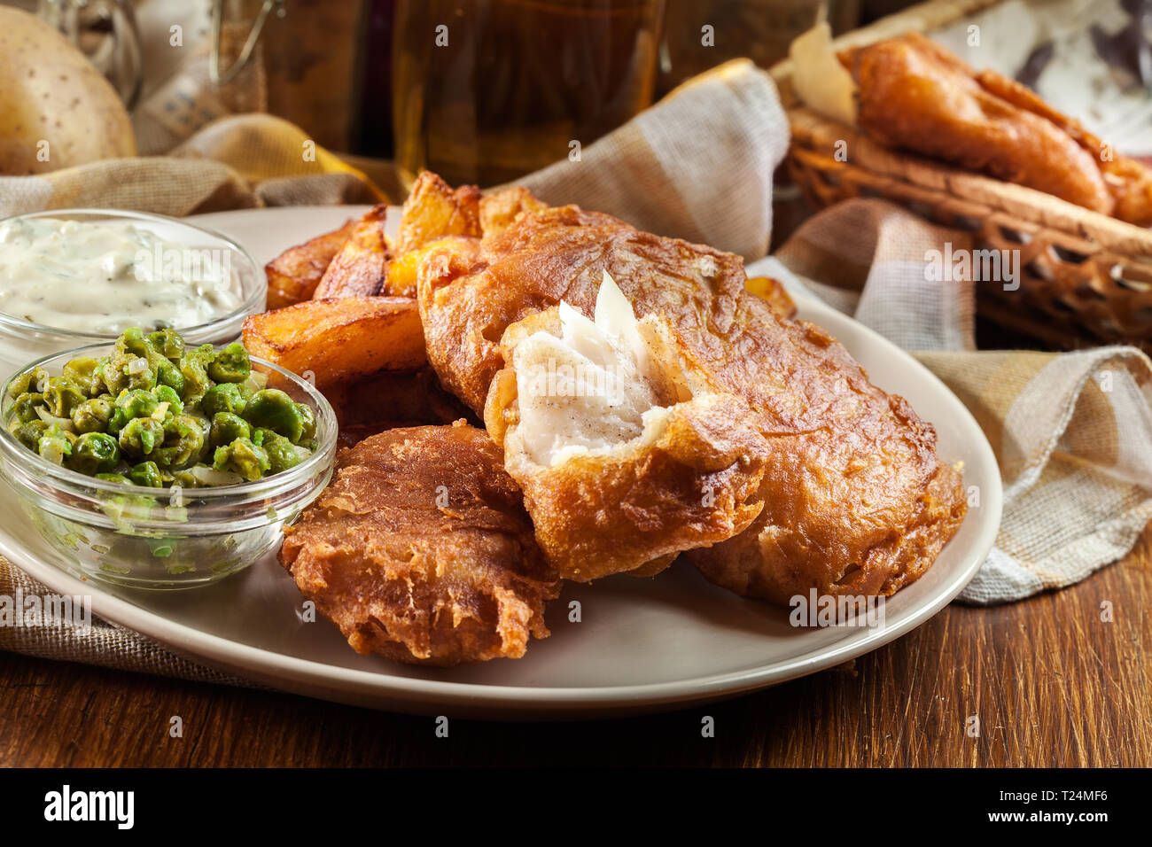 Le poisson dans la pâte traditionnelle de la bière et des frites avec de petits pois et sauce tartare Banque D'Images
