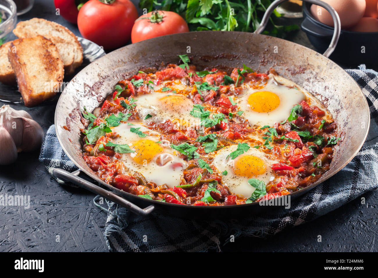 Shakshuka dans une poêle. Plat traditionnel du Moyen-Orient avec les œufs, tomates, poivrons, légumes et fines herbes. Banque D'Images