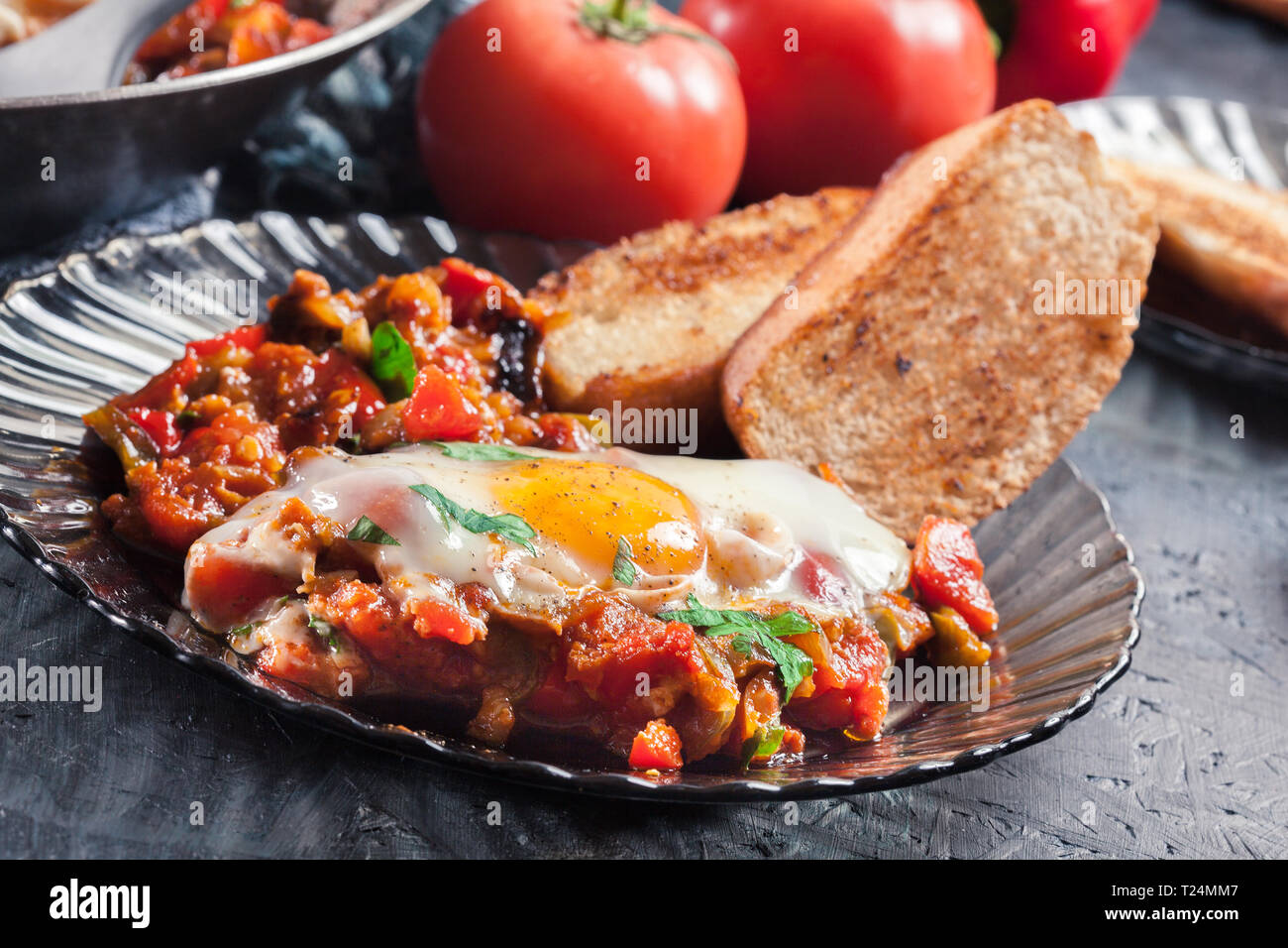 Partie de shakshuka sur une assiette. Plat traditionnel du Moyen-Orient avec les œufs, tomates, poivrons, légumes et fines herbes. Banque D'Images