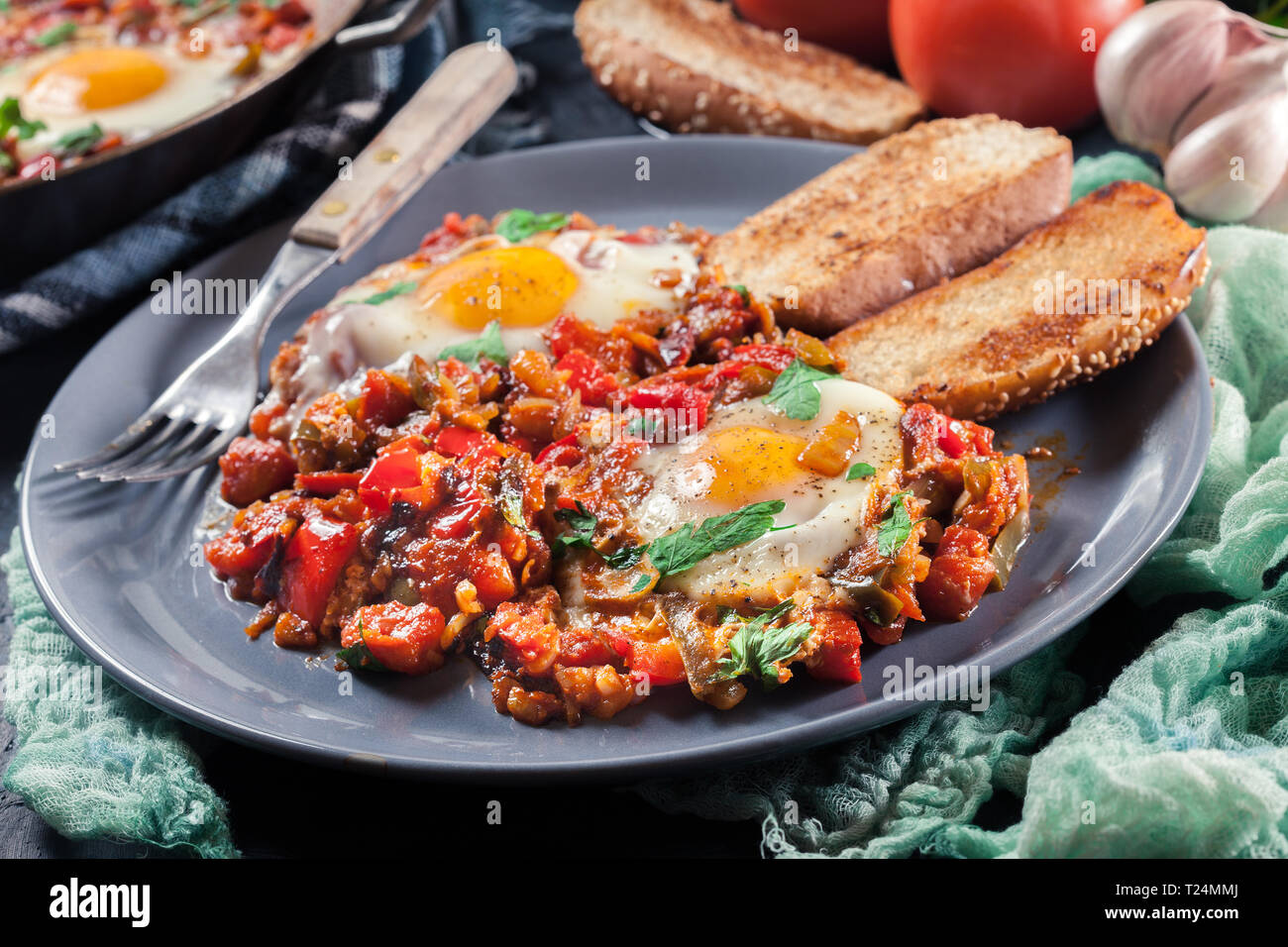 Partie de shakshuka sur une assiette. Plat traditionnel du Moyen-Orient avec les œufs, tomates, poivrons, légumes et fines herbes. Banque D'Images