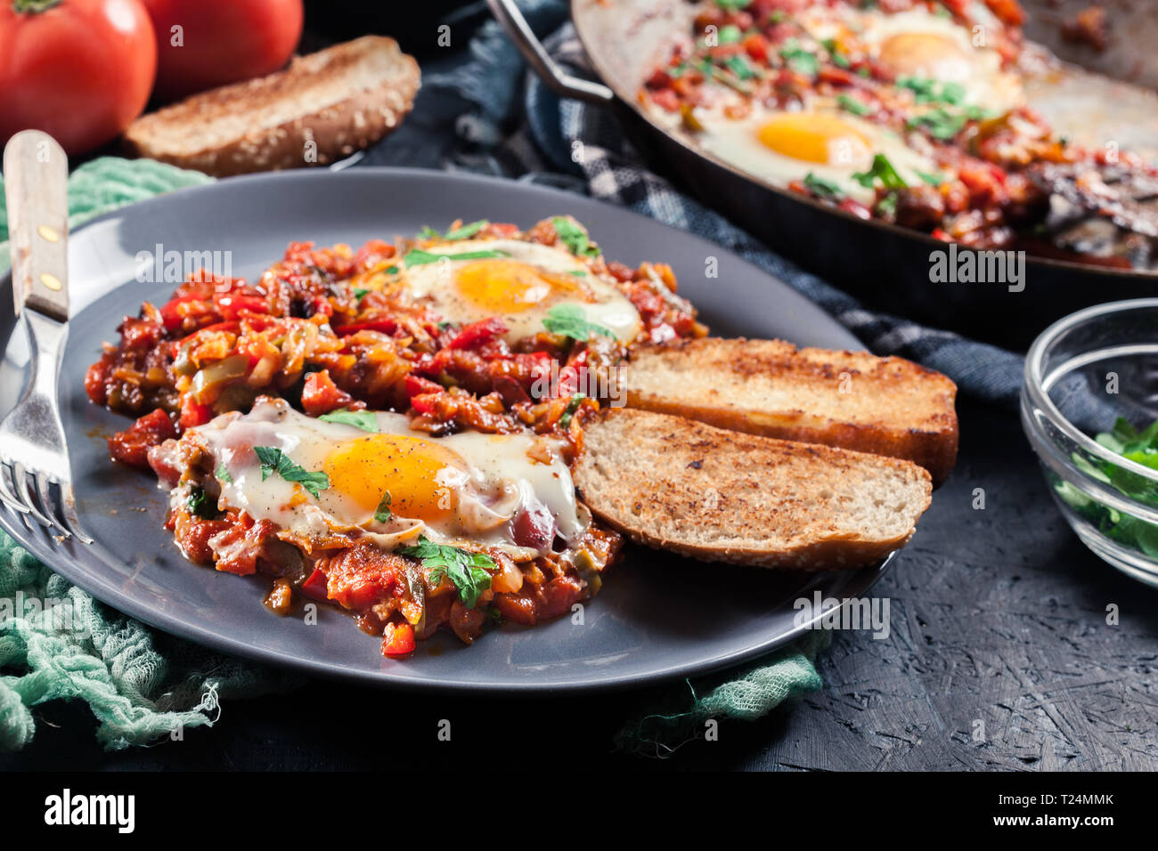 Partie de shakshuka sur une assiette. Plat traditionnel du Moyen-Orient avec les œufs, tomates, poivrons, légumes et fines herbes. Banque D'Images