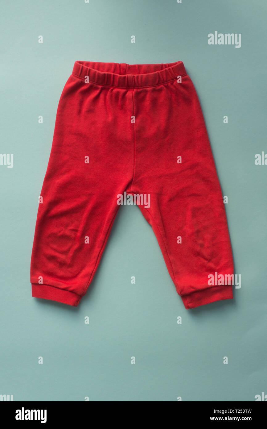 Bébé pantalon de sport rouge sur fond bleu. Banque D'Images