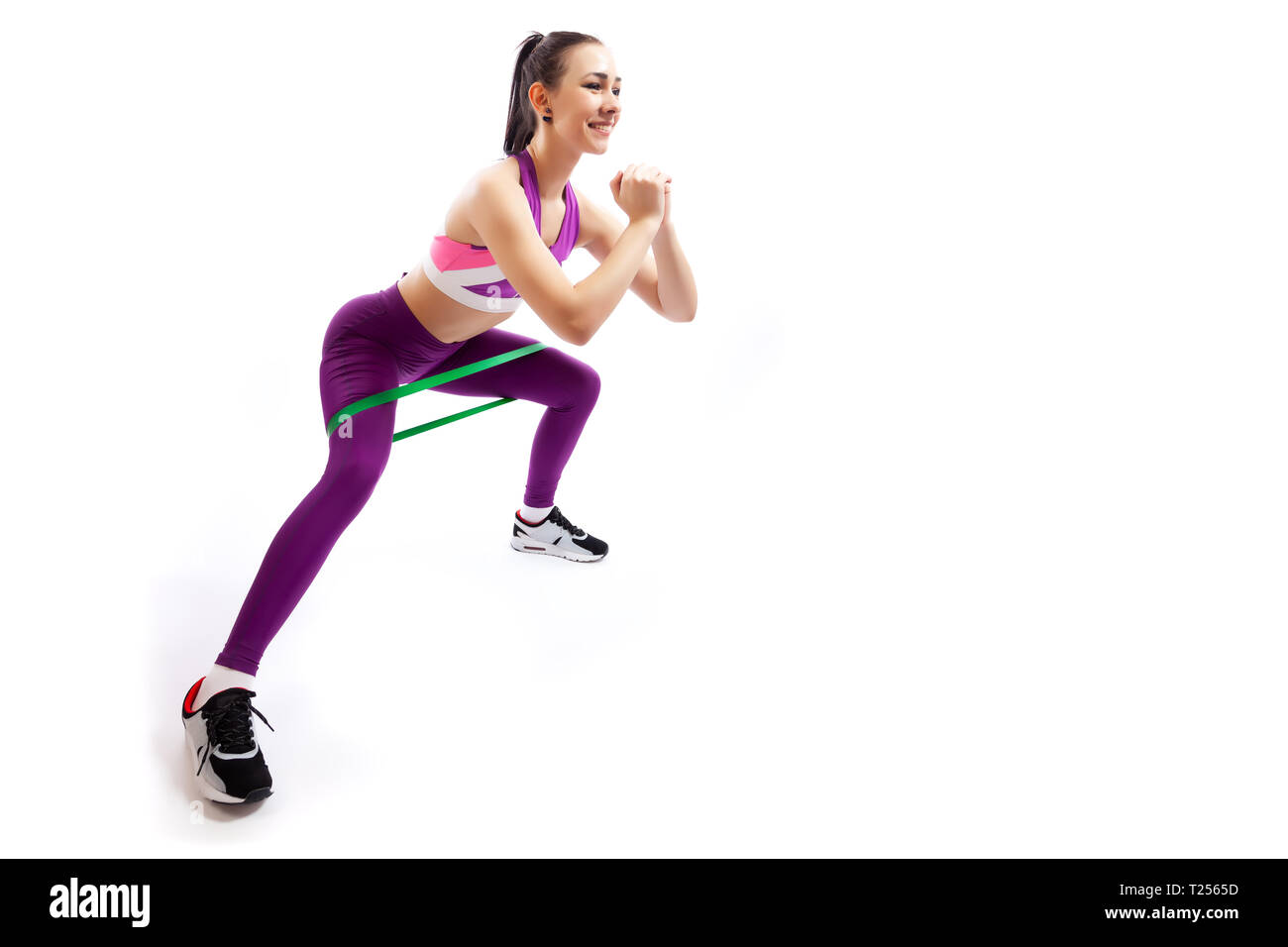 Une femme brune coach sportif dans une salle de sport et haut court rose  indique la bonne technique d'accroupissement avec sport, bandes de  caoutchouc ; la position d'un Photo Stock - Alamy