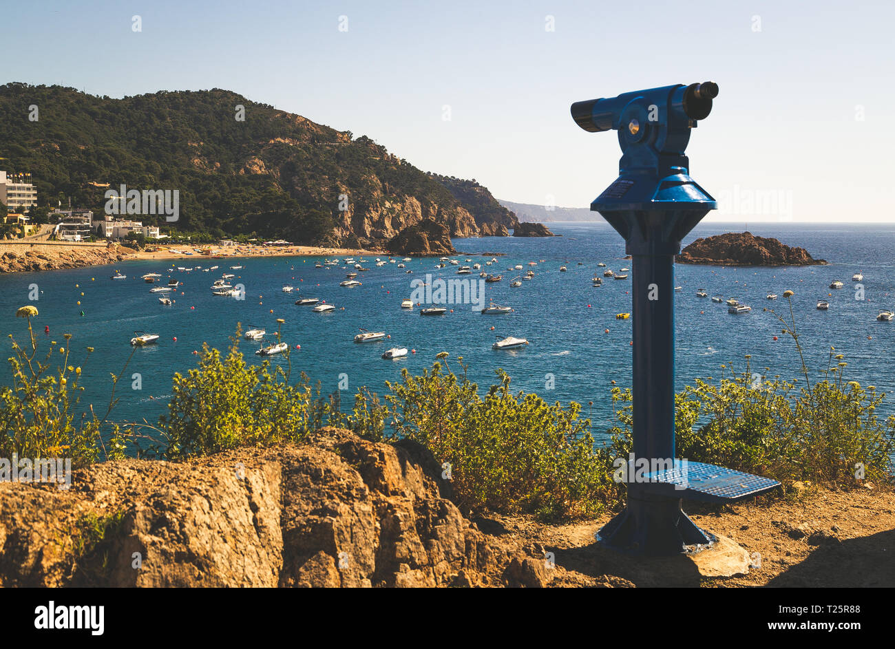 La plage et la baie de Tossa de Mar, Espagne. Il y a un télescope bleu à l'avant-plan. Banque D'Images