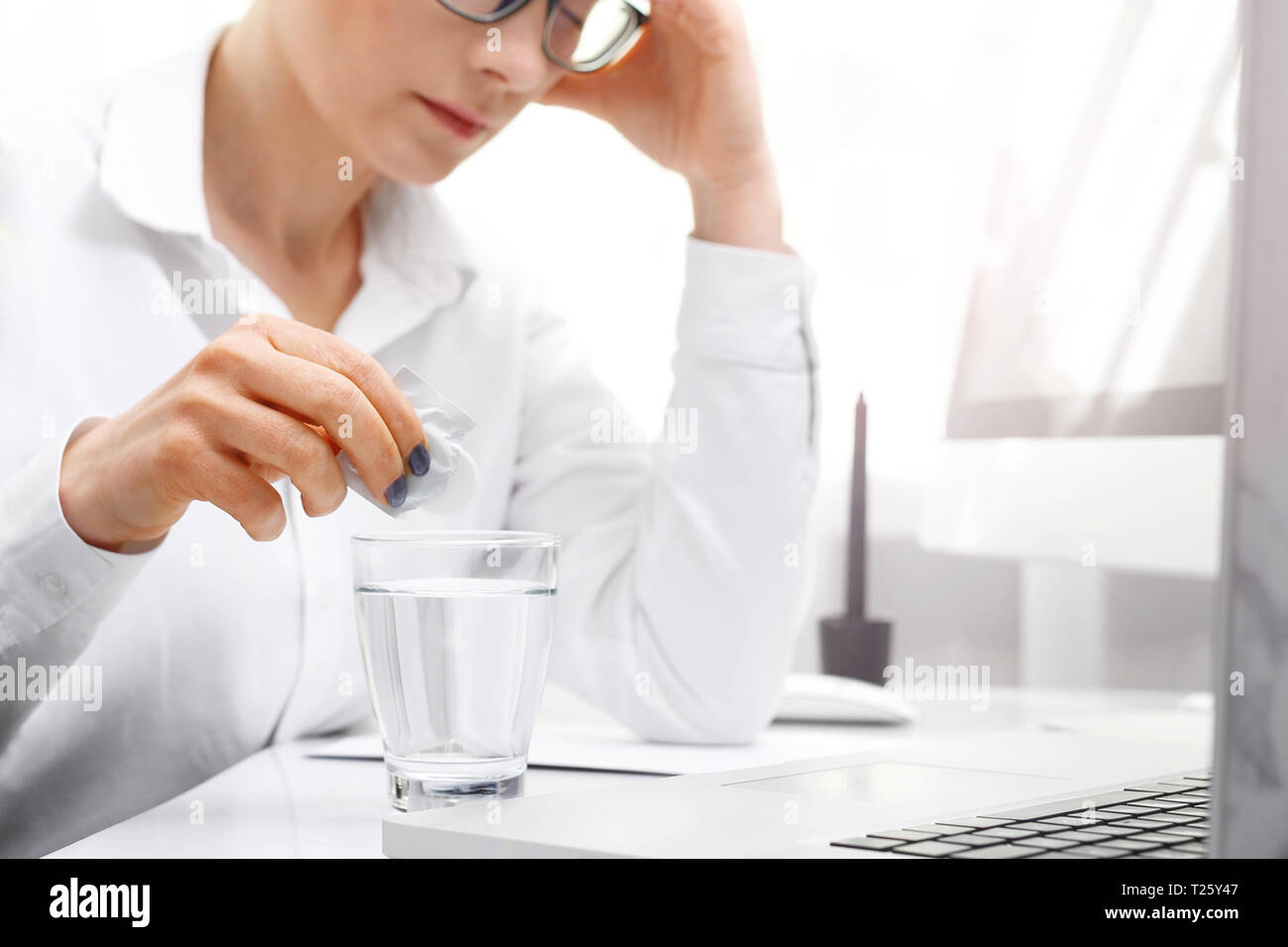Comprimé analgésique. Une femme au travail dissout l'effervescent comprimé analgésique. Banque D'Images