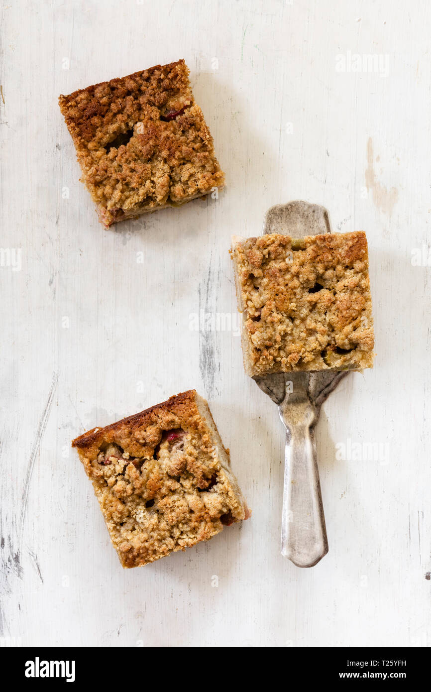 Trois morceaux de gâteau à la rhubarbe et d'un cake server sur bois blanc Banque D'Images