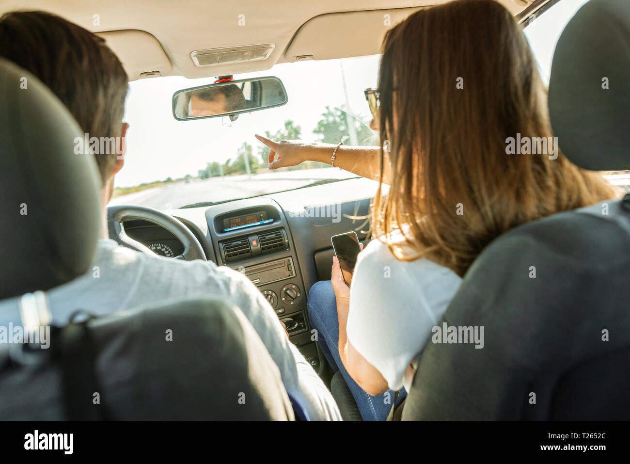 Couple roulant en voiture avec femme en pointant son doigt du siège passager Banque D'Images