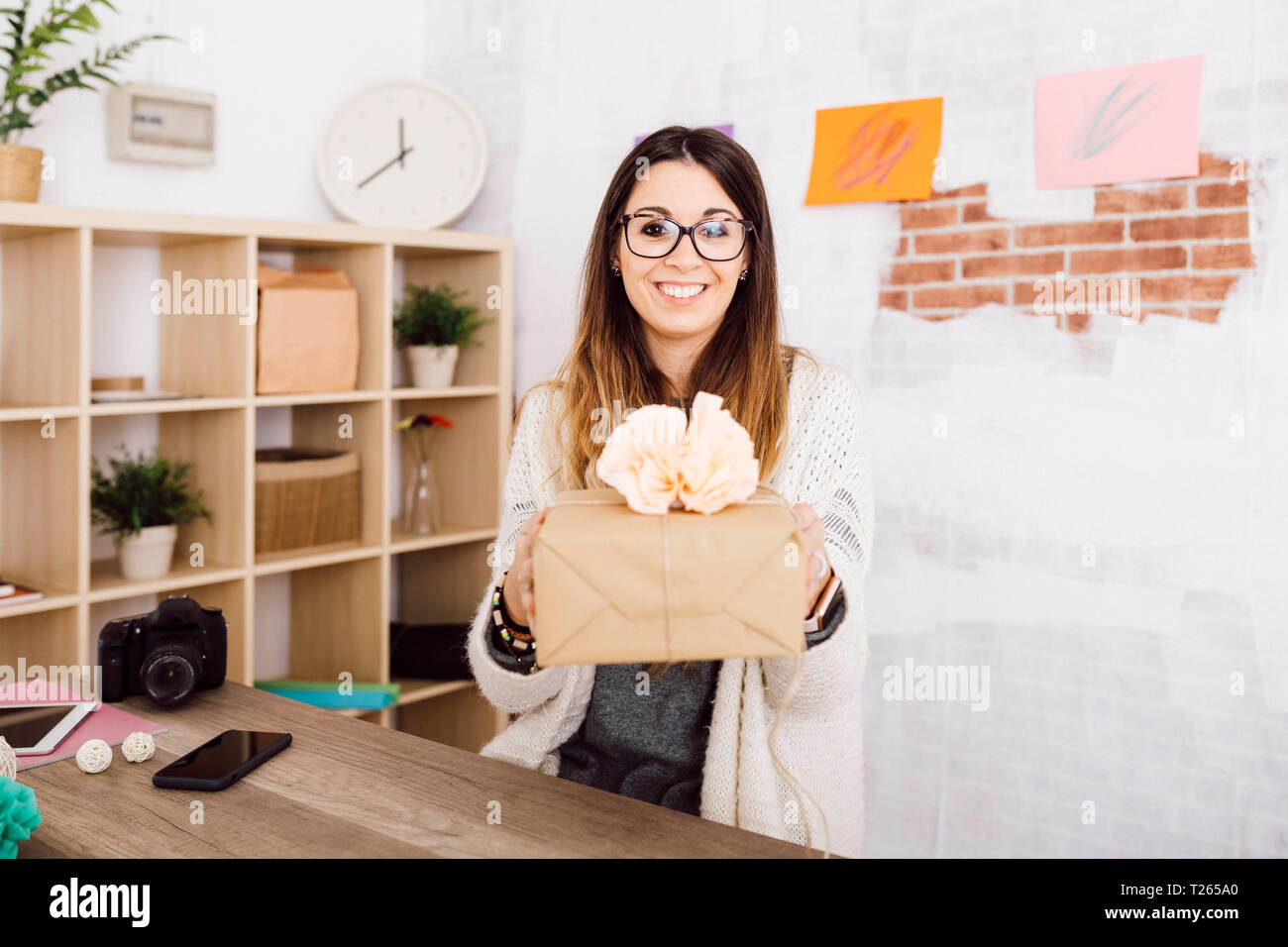 Jeune femme montrant un cadeau enveloppé dans son studio Banque D'Images