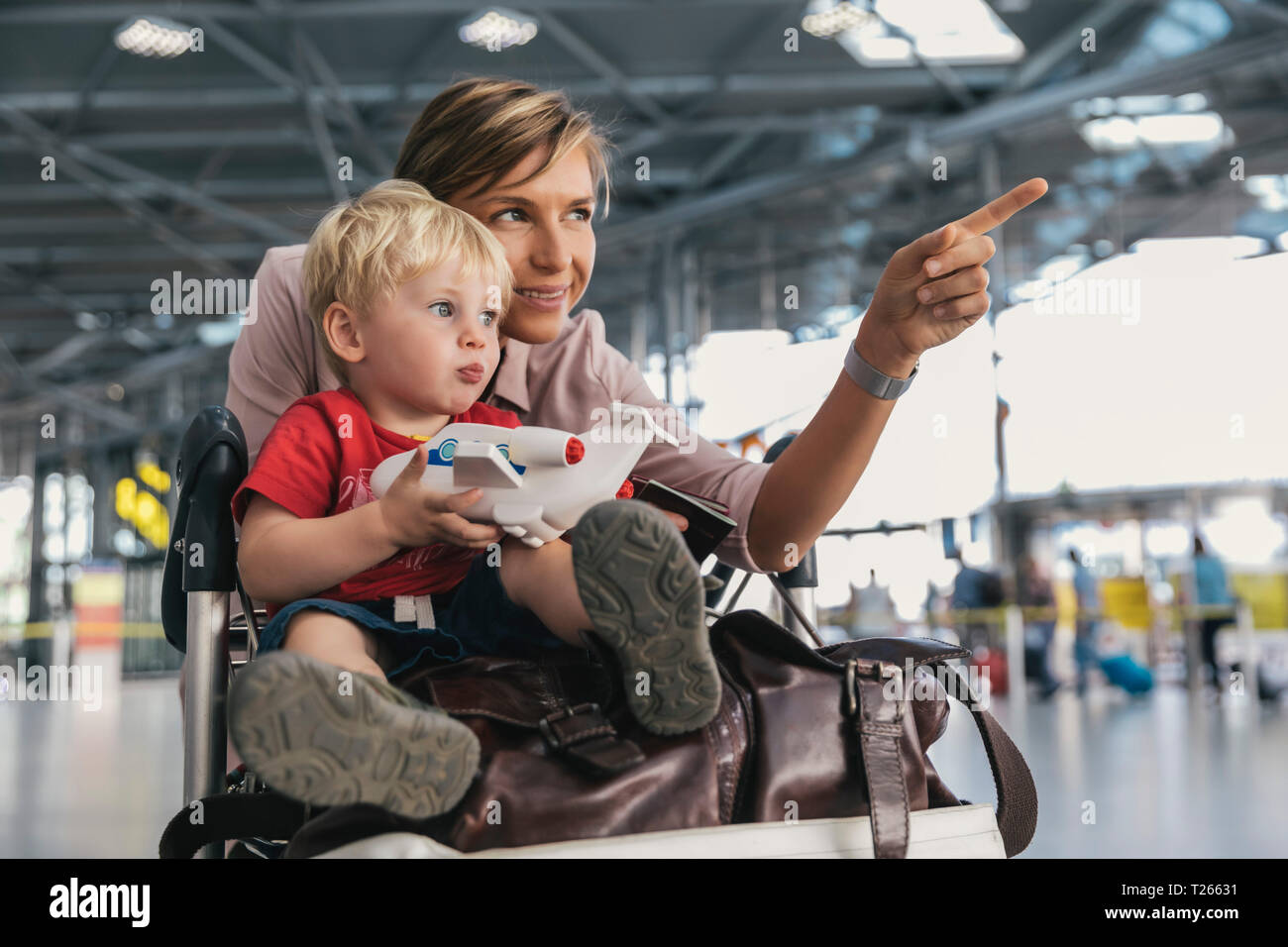 Allemagne, Cologne, portrait de mère et petit fils avec chariot à bagages à l'aéroport Banque D'Images