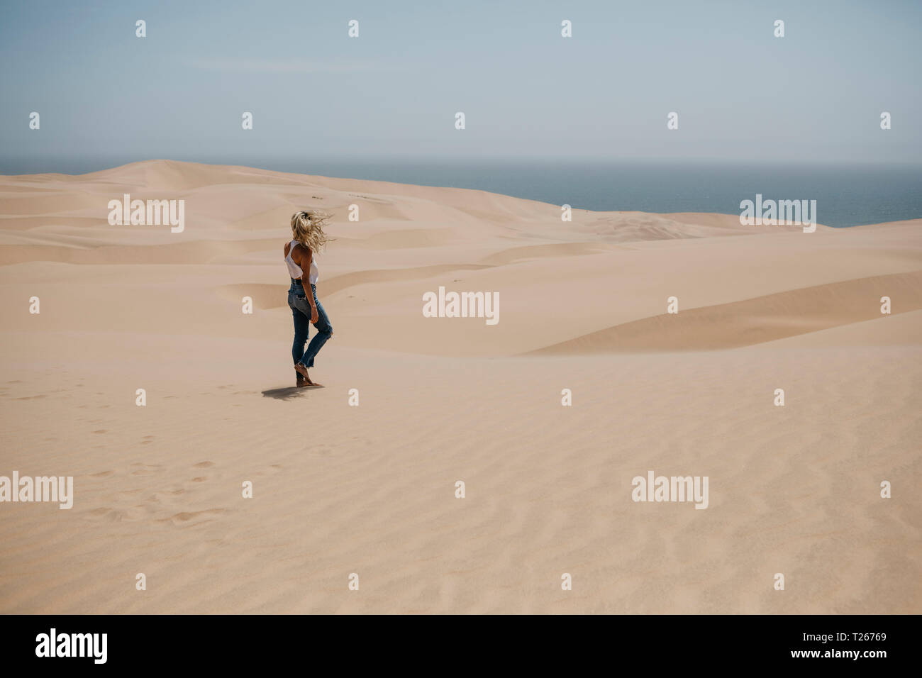 La Namibie, Walvis Bay, Namib-Naukluft National Park, Sandwich Harbour, femme marche dans le paysage de dunes Banque D'Images
