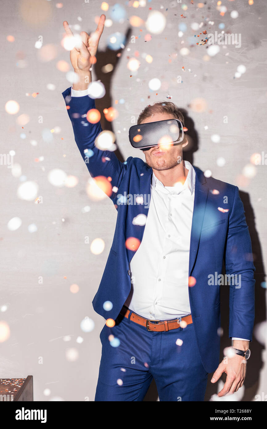 Jeune homme avec des lunettes de réalité virtuelle en permanent entre confetti douche lors d'une fête Banque D'Images