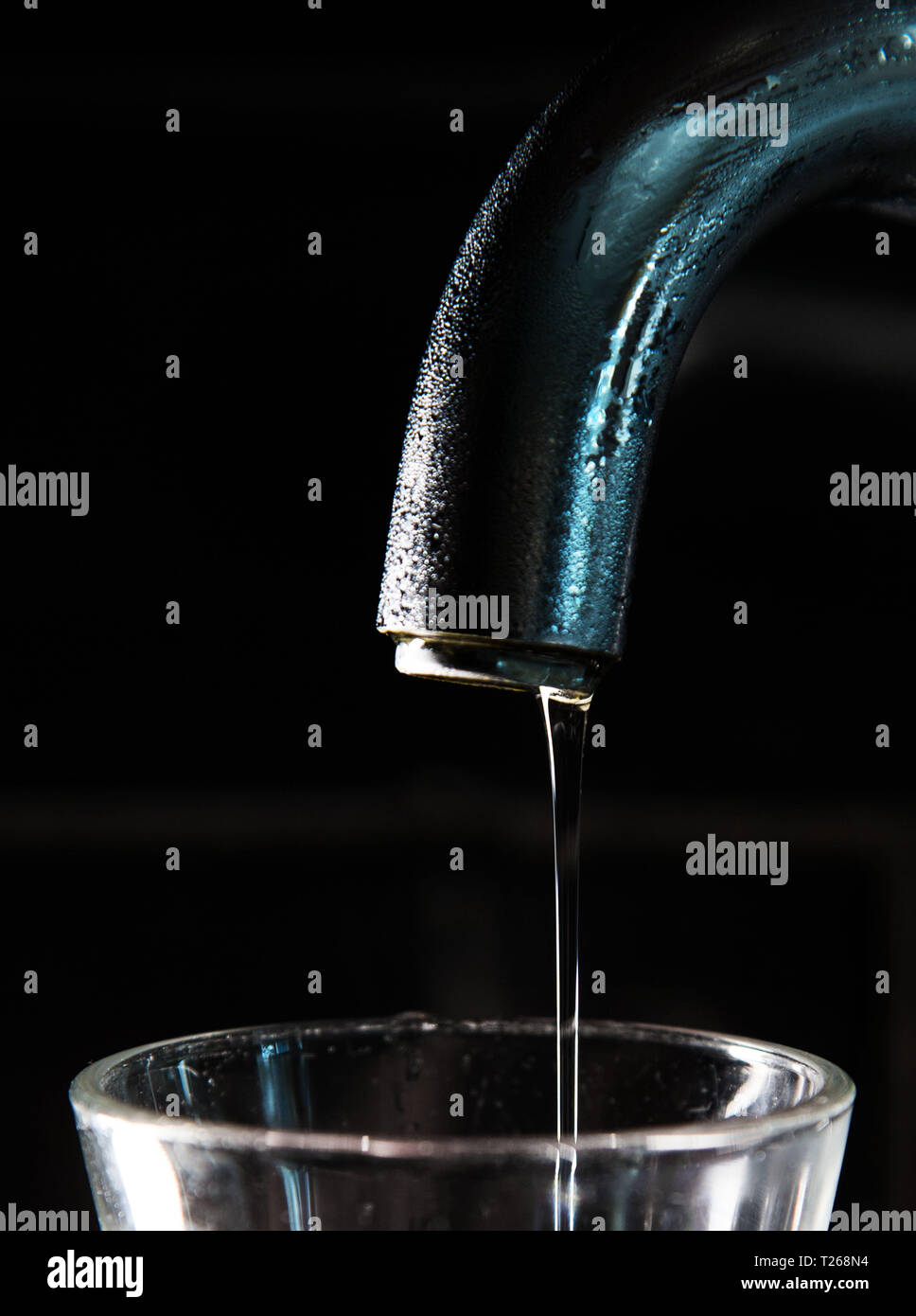 Les pénuries d'eau. Quelqu'un verse de l'eau dans un verre d'un robinet dans une cuisine. Banque D'Images