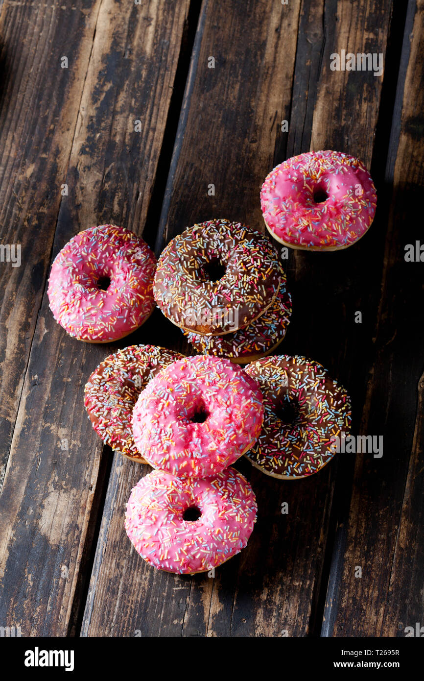 Donuts colorés sur bois avec sprinkles sucre Banque D'Images