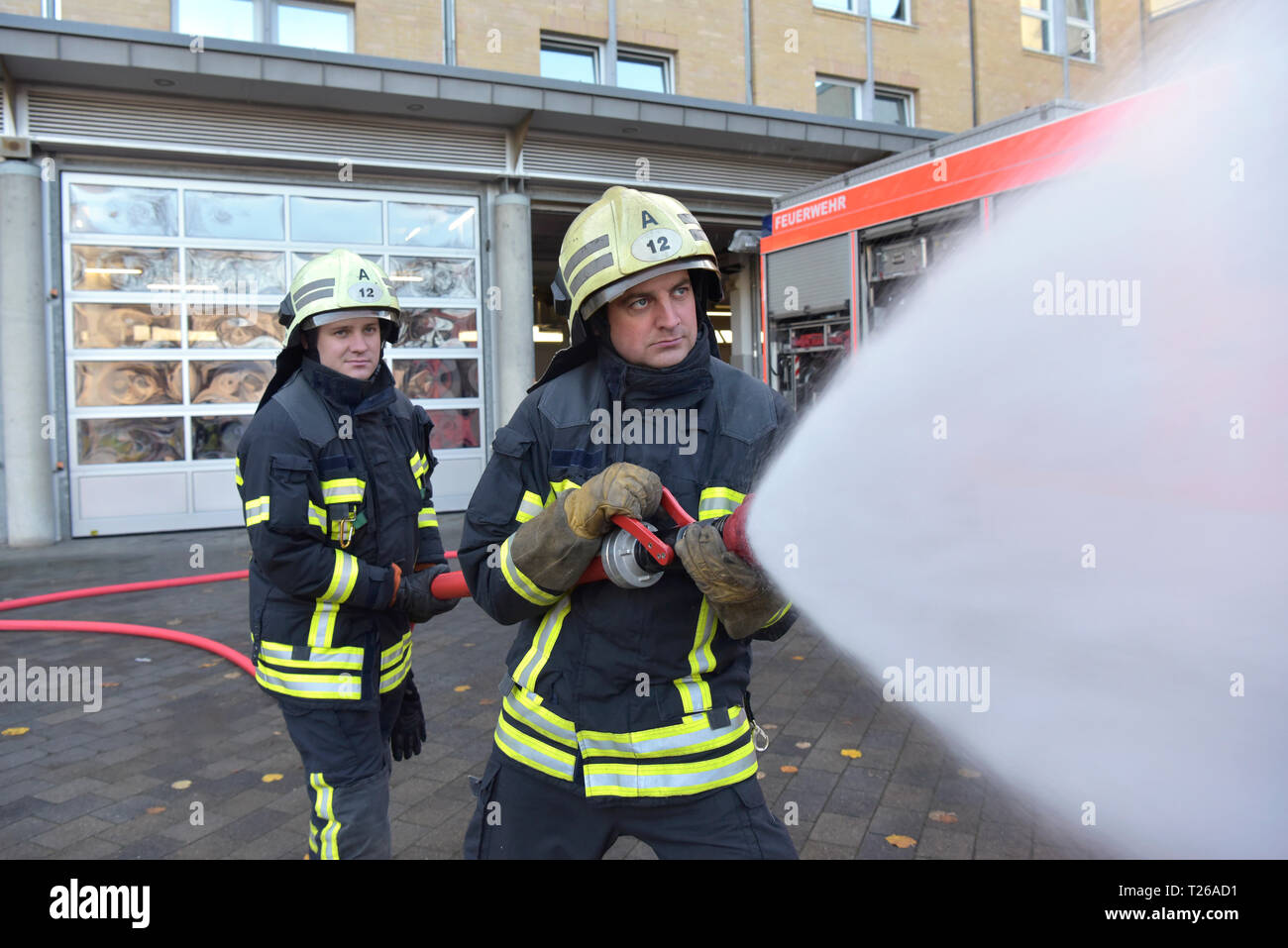 Deux pompiers debout sur l'eau d'extinction de l'exercice avec cour Banque D'Images
