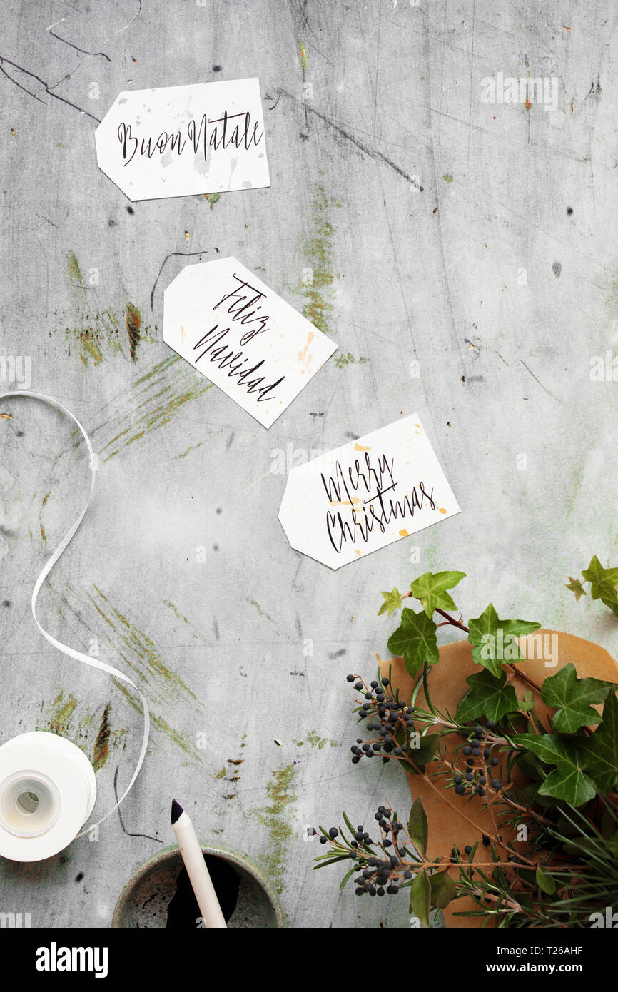 Joyeux Noël écrit en 3 langues différentes (français, italien, espagnol) sur les étiquettes cadeaux calligraphie Banque D'Images