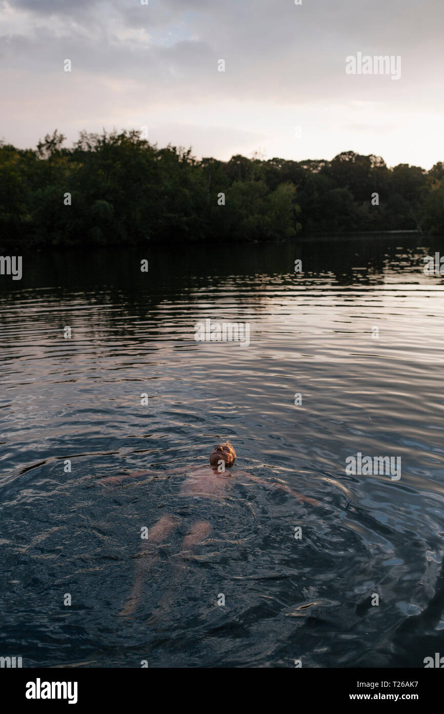 Man la baignade dans un lac au coucher du soleil Banque D'Images