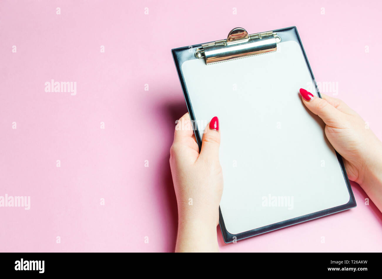 La jeune fille tient une tablette vide pour les enregistrements sur un fond rose. La notion de contrôle et d'inventaire. Records et méthode de travail. Intégrale, Banque D'Images