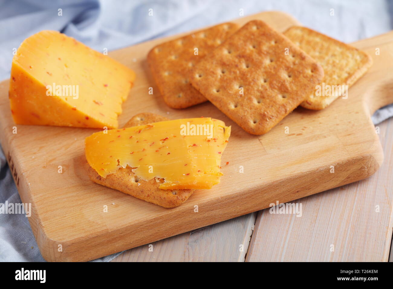 Les craquelins avec du fromage gouda épicé et une tranche de fromage sur une planche en bois Banque D'Images