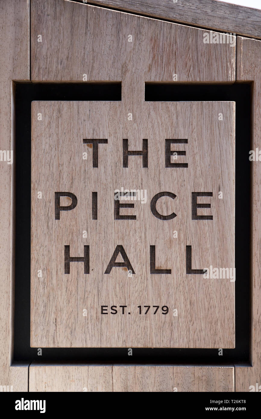 La Pièce Hall logo dans la partie bois d'un banc public dans le quadrilatère de la place centrale . Graines de soleil et ciel bleu. Halifax, West Yorkshire, Royaume-Uni. (106) Banque D'Images