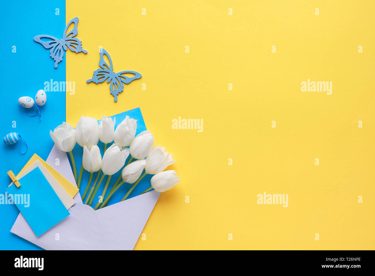 Télévision Pâques réside dans le jaune et bleu. Tulipes blanches dans une enveloppe sur le papier de fond avec des œufs décoratifs et de papillons, copiez-space Banque D'Images