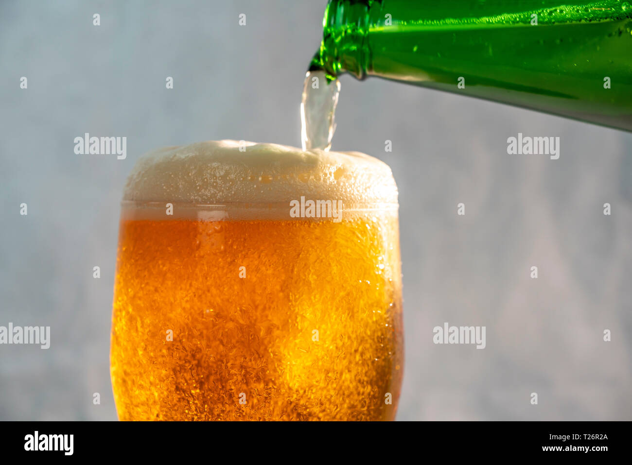 Servir la bière dans un verre d'une bouteille verte Banque D'Images