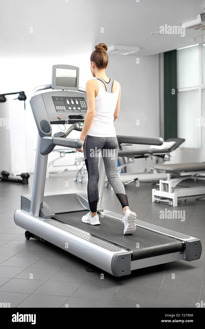 Une jeune femme dans une salle d'exercice est en cours d'exécution sur un tapis roulant automatique. Banque D'Images