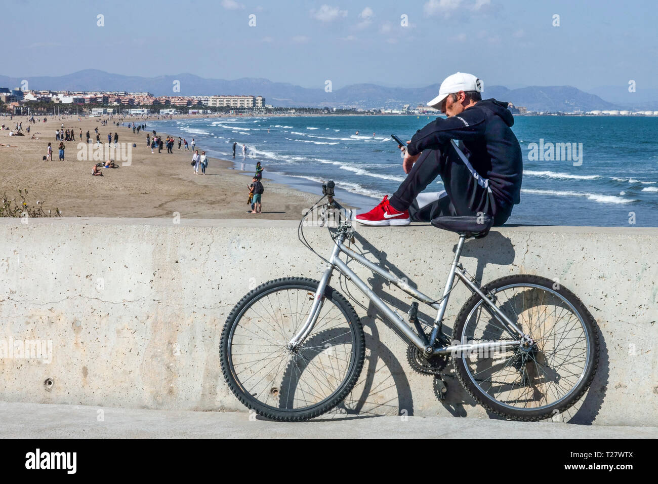Biker prend une pause à la communication mobile, Malvarrosa plage arrière-plan, Valencia plage Espagne vue sur la mer Banque D'Images