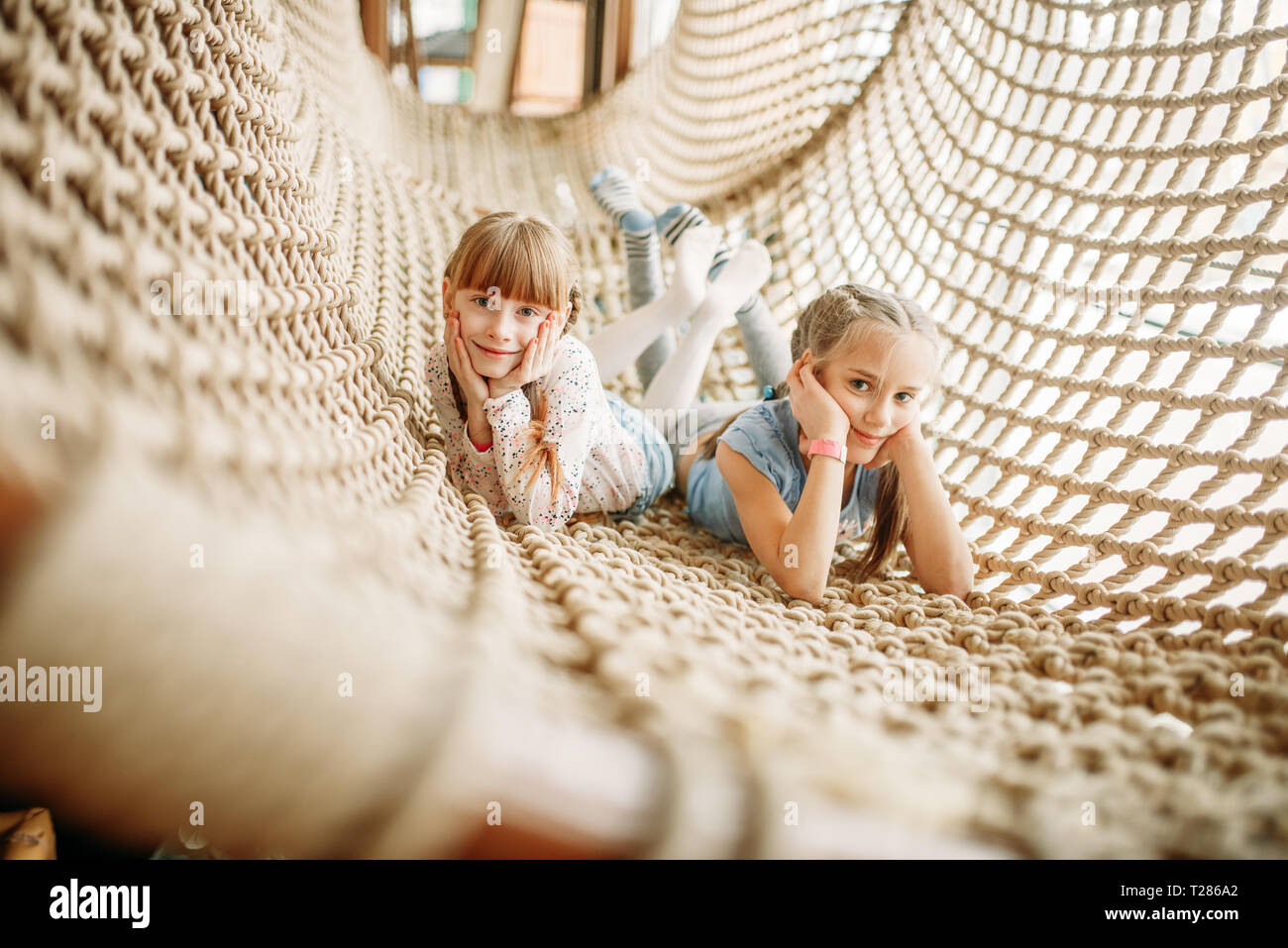 Deux funny girls pose à la corde chez les enfants net game center. Childs excités s'amuser sur l'aire de l'intérieur. Les enfants jouant dans une salle de jeux Banque D'Images