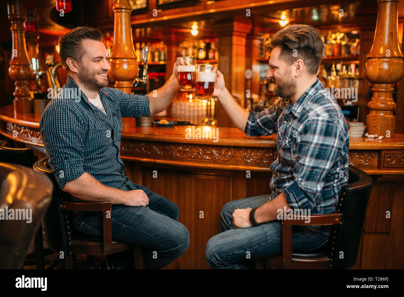 Deux male amis boit de la bière au comptoir dans un pub. Les barbus avec café, s'amusant en bars, de bons amis Banque D'Images