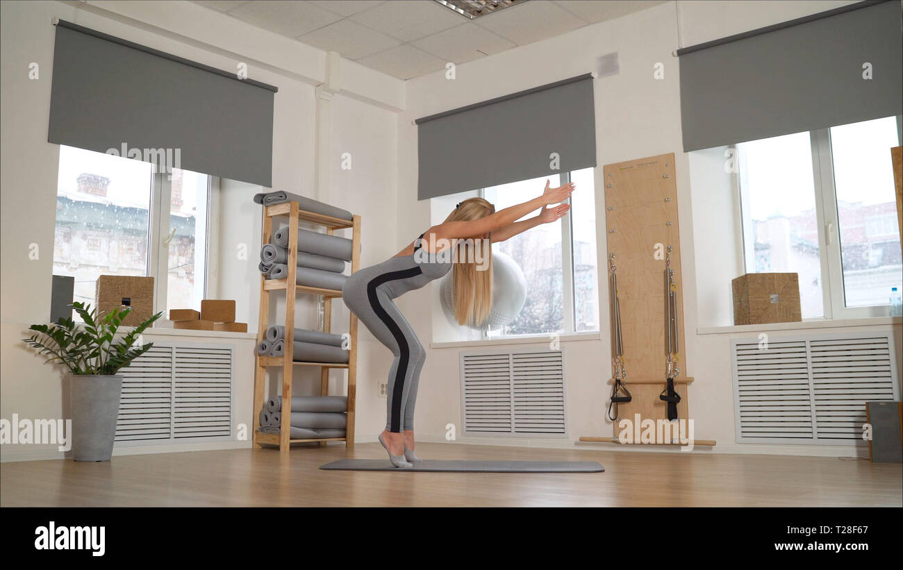 Athletic jeune fille brune dans un costume gris s'est engagé dans l'étirement. Fille Slim engagées professionnellement dans Pilates. Banque D'Images