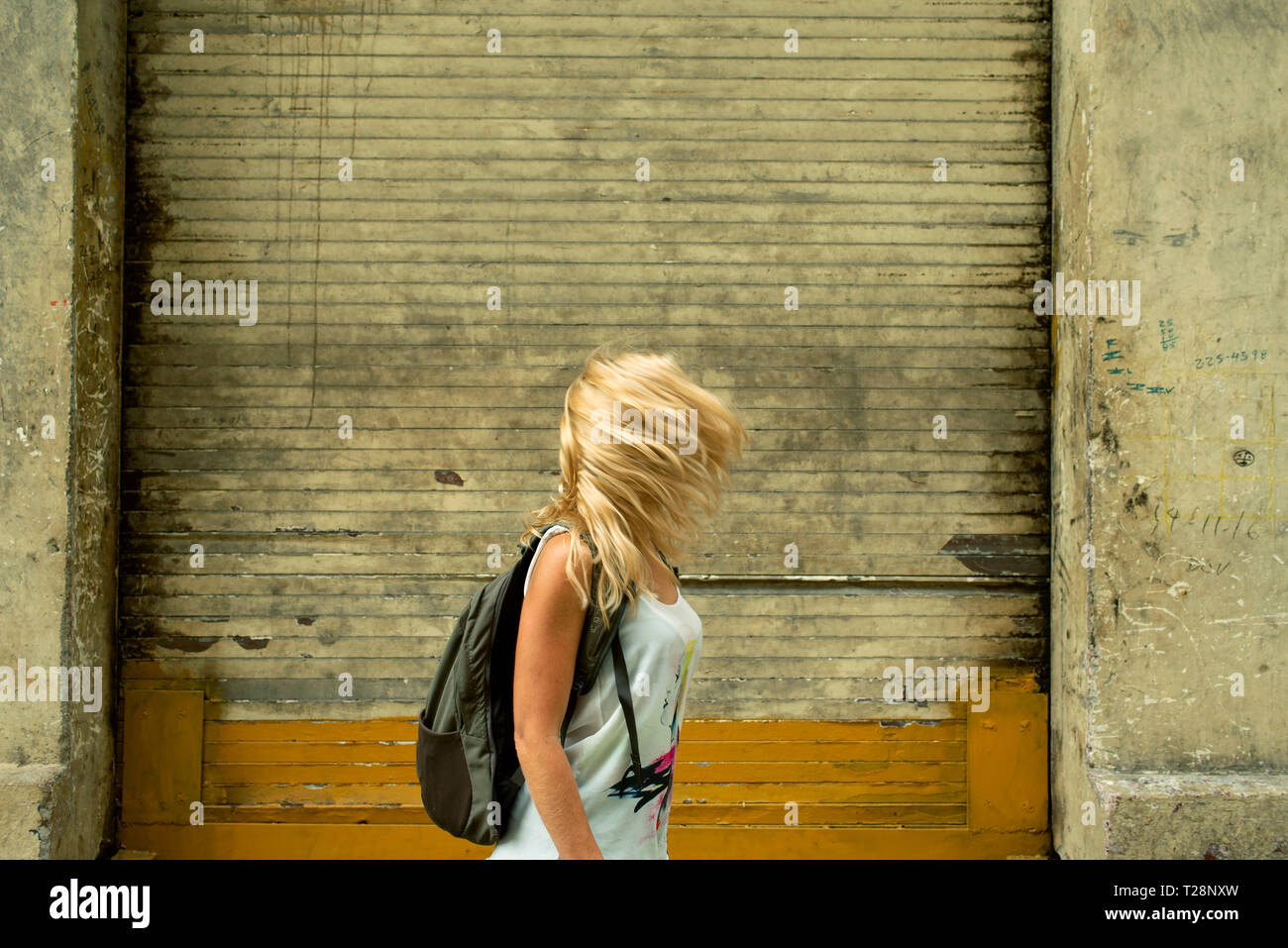Femme blonde en passant par la toile urbaine de vent avec un couvre le visage. Voyage / backpacker concept, RF. Banque D'Images