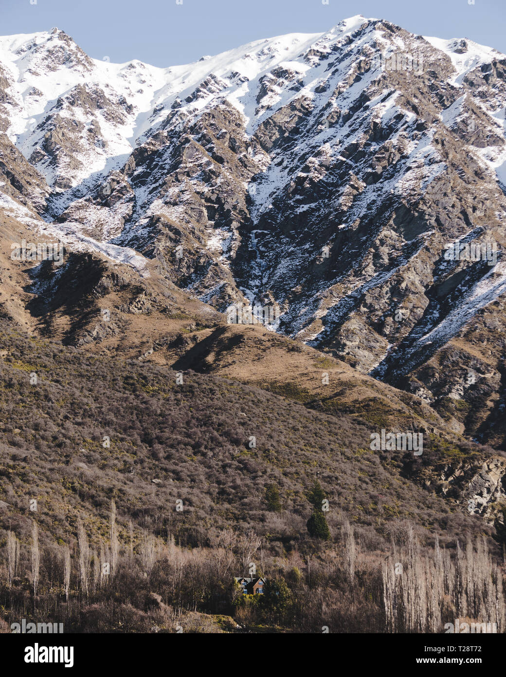 Petite maison au fond d'une immense montagne magnifique dans le sud de l'île de la Nouvelle-Zélande sur une belle journée ensoleillée. Banque D'Images