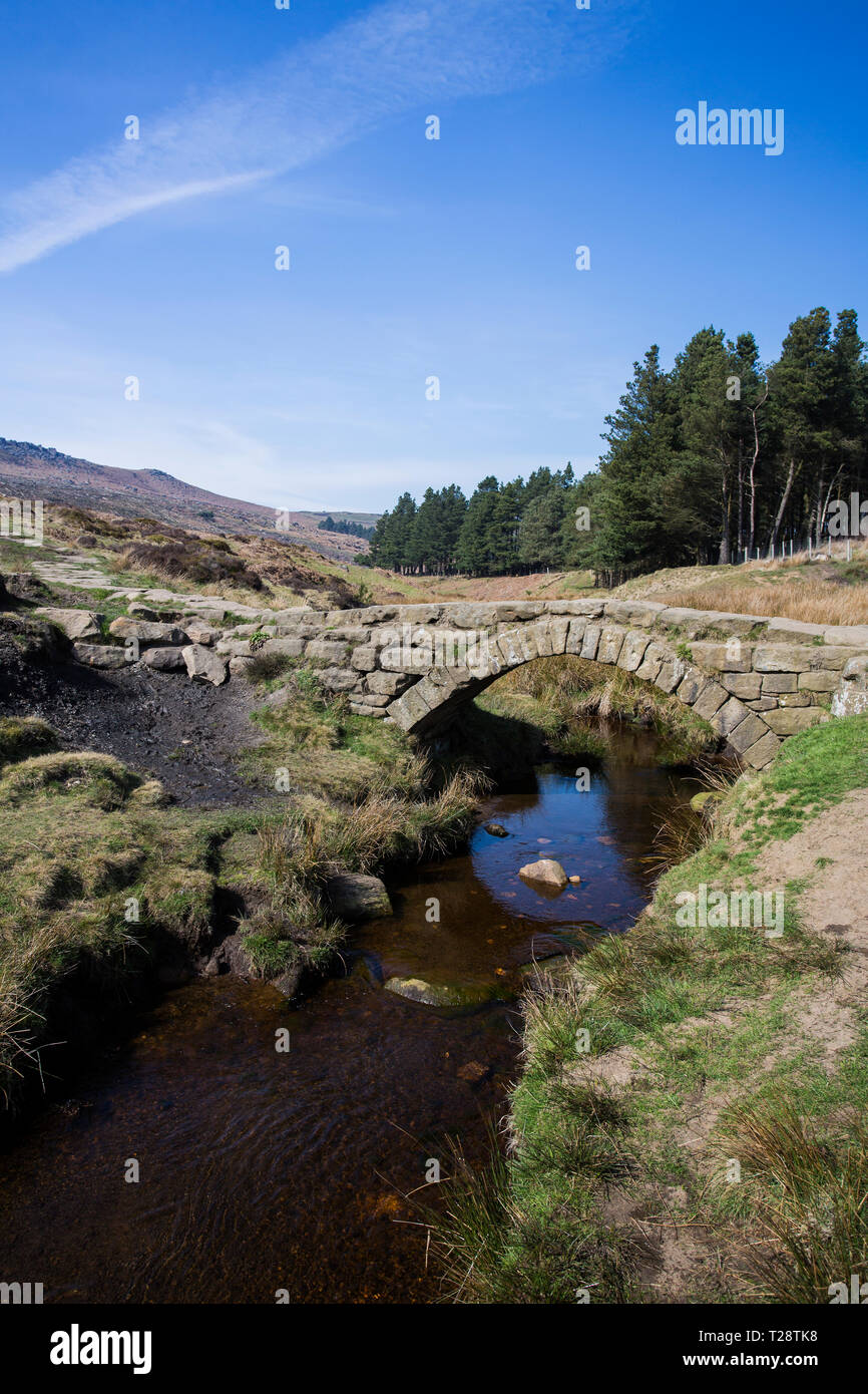 Un vieux pont de pierre pour les charrettes sur un petit ruisseau dans le Peak District National Park Banque D'Images