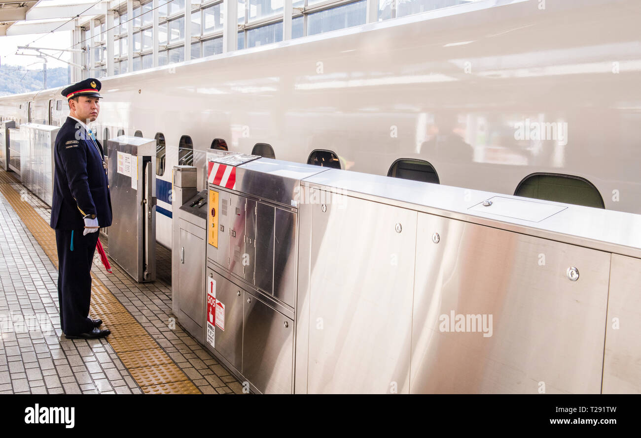 Chef d'orchestre en uniforme, debout sur le quai, tenant un drapeau, en Shinkansen, le train station, Himeji, Japon Banque D'Images