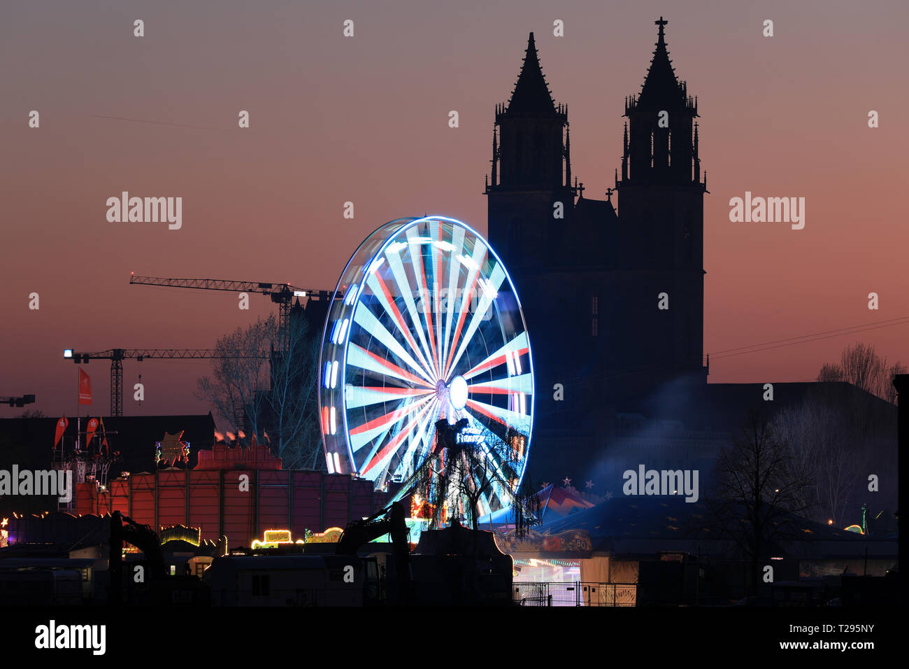 Magdeburg, Allemagne. 30Th Mar, 2019. Une grande roue brille en face de la silhouette de la cathédrale 'Saint Joseph et Saint Maurice' dans la capitale de l'État à la 571 e Magdeburg Foire de Printemps. Jusqu'à 22.04.2019 Les visiteurs peuvent visiter le mile avec manèges et stands sur la Kleine Stadtmarsch chaque jour. Crédit : Peter Gercke/dpa-Zentralbild/dpa/Alamy Live News Banque D'Images