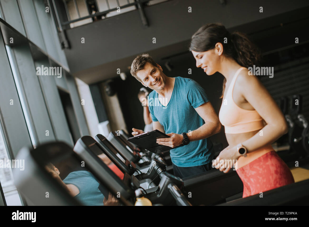 Jeune femme avec travail formateur sur tapis roulant dans une salle de sport Banque D'Images