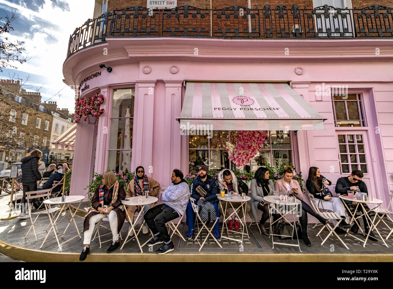 Les gens assis à l'extérieur de Peggy Porschen gâteaux, à Belgravia , un magasin de gâteaux connu pour son extérieur rose pastel frappant, Londres, Royaume-Uni Banque D'Images