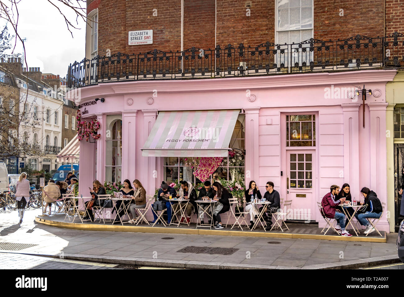 Les gens assis à l'extérieur de Peggy Porschen gâteaux, à Belgravia , un magasin de gâteaux connu pour son extérieur rose pastel frappant, Londres, Royaume-Uni Banque D'Images