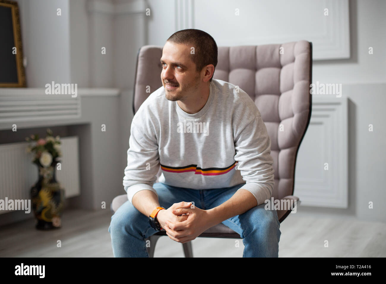 L'homme assis sur une chaise et à la recherche sur le côté dans la pièce et souriant Banque D'Images