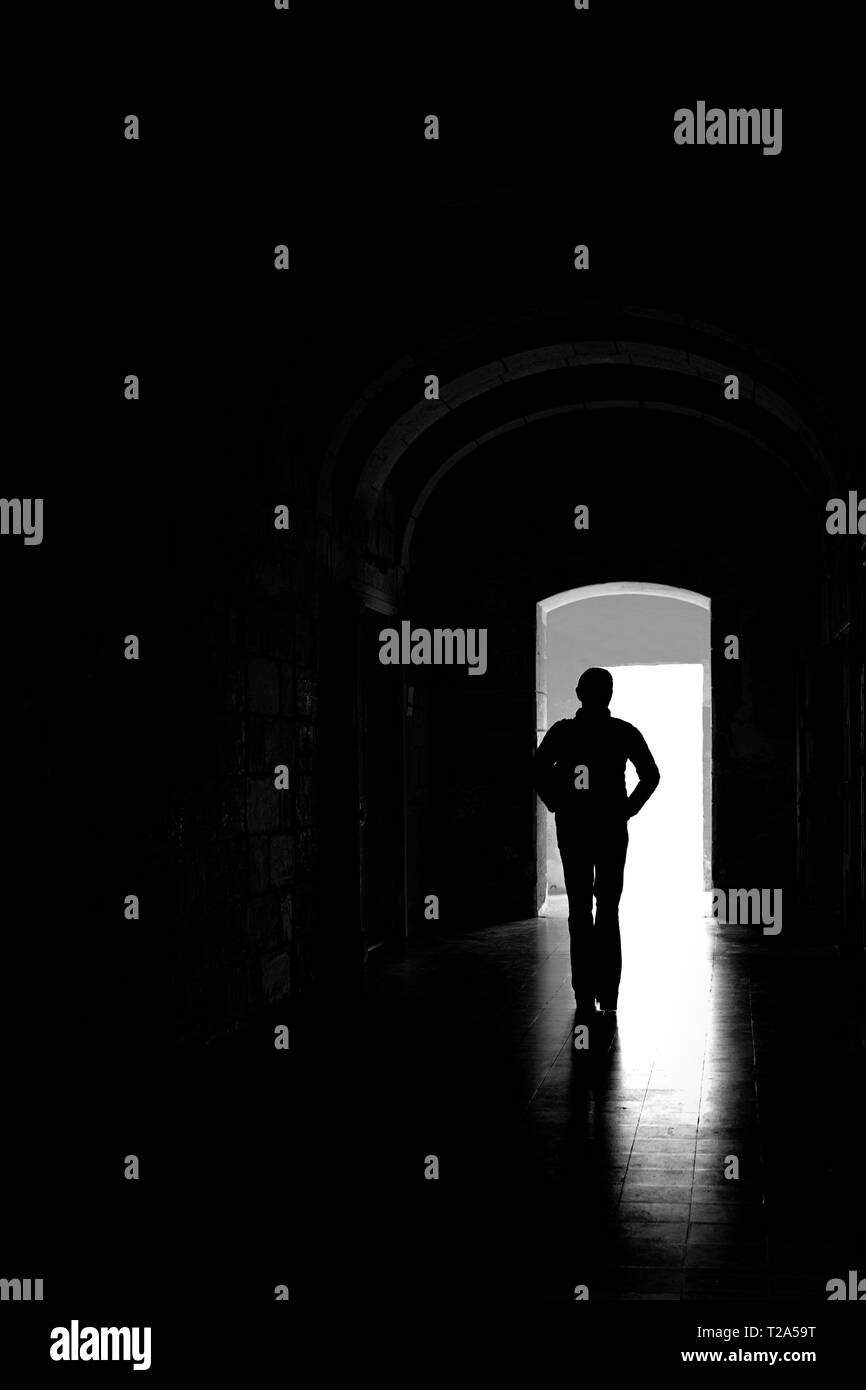 Figure solitaire, silhouetted, marchant à travers un couloir sombre. Banque D'Images