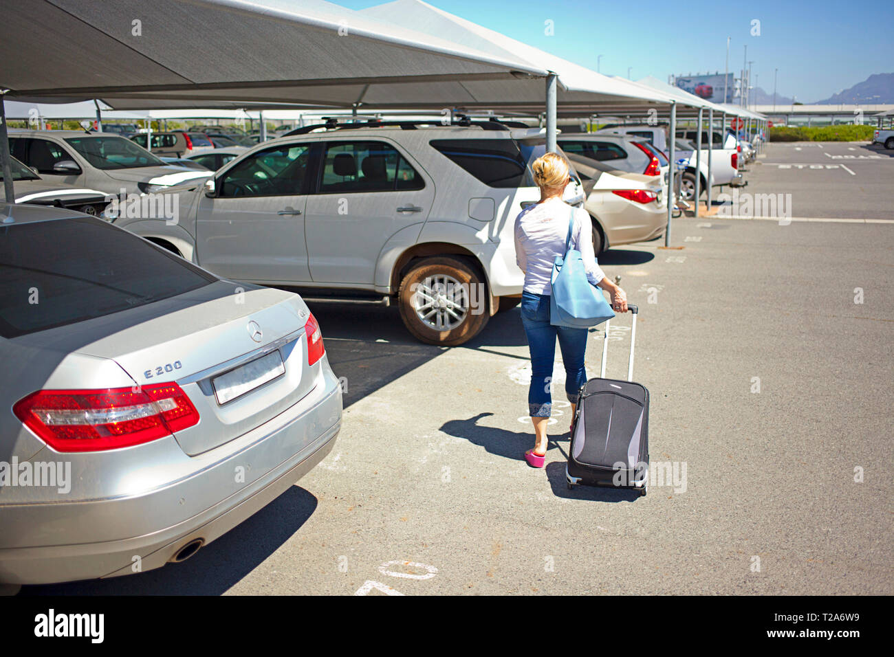 Femme marchant avec une valise pour aller en voiture, l'aéroport international du Cap Banque D'Images