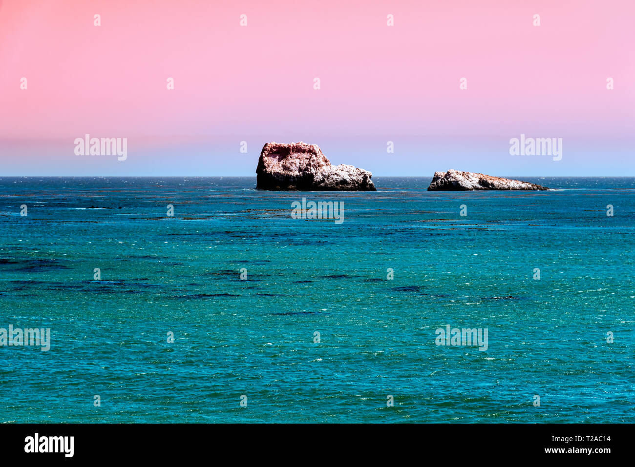 Donnant sur l'océan bleu au coucher du soleil au ciel rose pastel. Banque D'Images