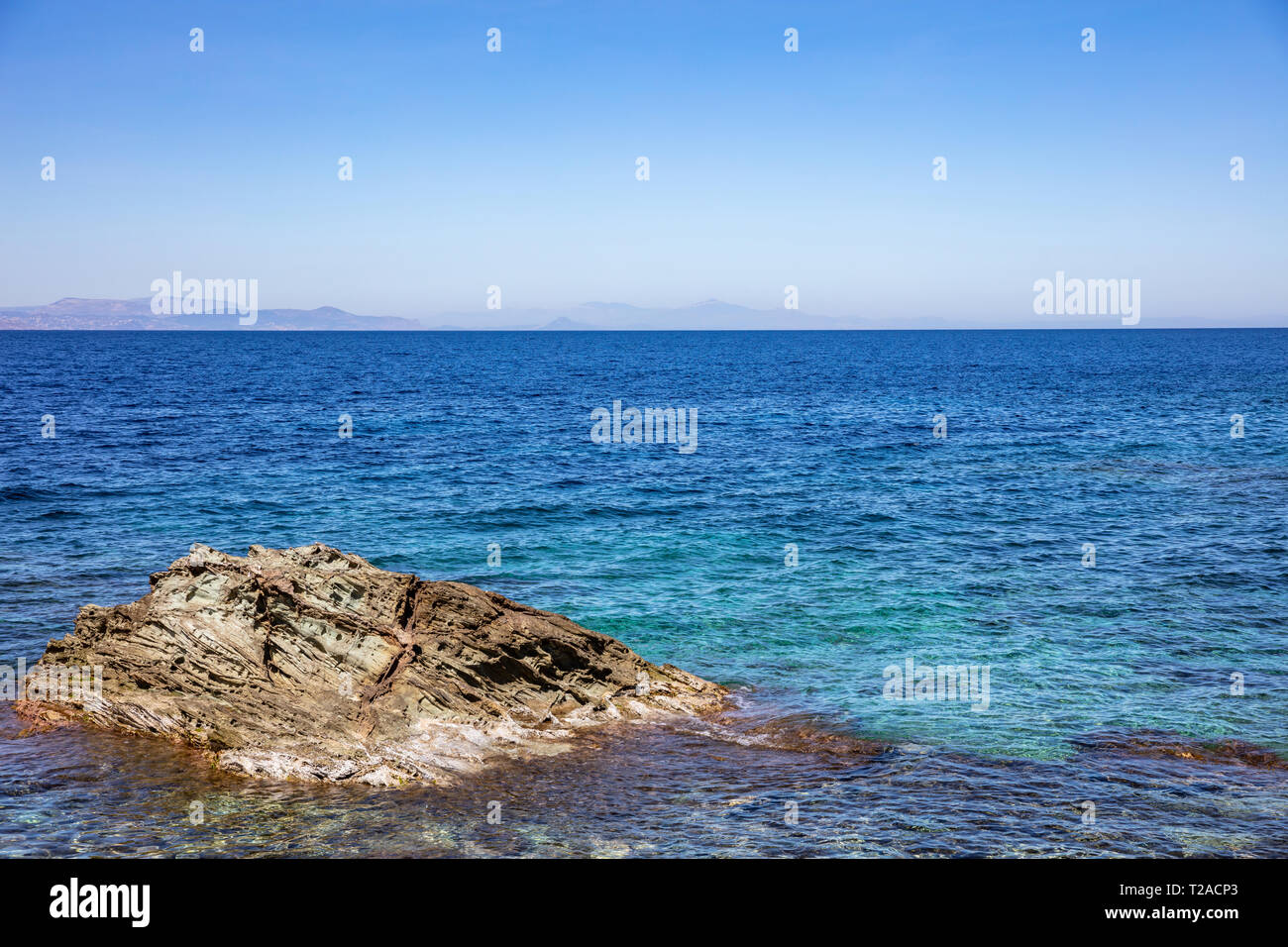 La Grèce. Mer Égée, bleu ciel clair et une mer calme. Un gros rocher dans la mer Banque D'Images