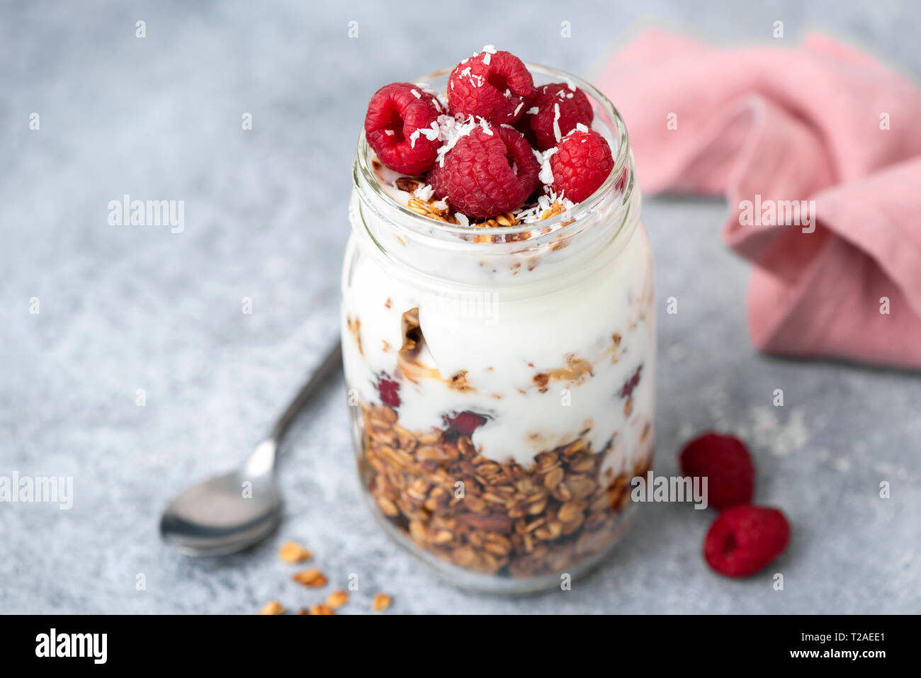 Granola, yogourt et petits fruits en pot sur fond de table en béton. Vue rapprochée, selective focus. Délicieux petit déjeuner parfait avec du yaourt grec et croquante Banque D'Images