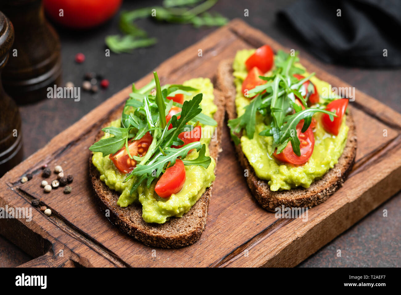 Végétarien ou Végétalien pain grillé avec purée d'avocat, roquette servi sur planche de bois Banque D'Images