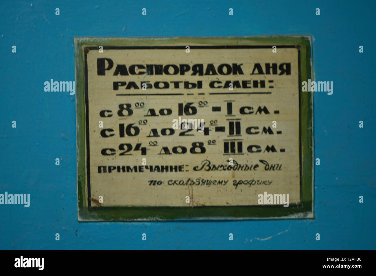 Le signe de la routine quotidienne dans l'ancienne font en russe. La plaque est vieux, sur un fond bleu Banque D'Images