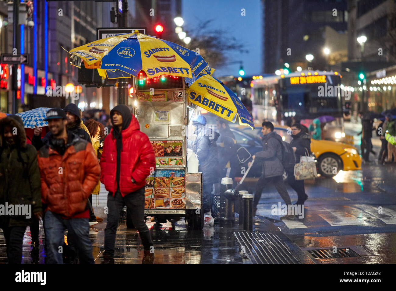 Rue de hot-dog vente de trader à partir de son panier sur la 8e avenue dans le noir soir, Manhattan, New York, USA Banque D'Images